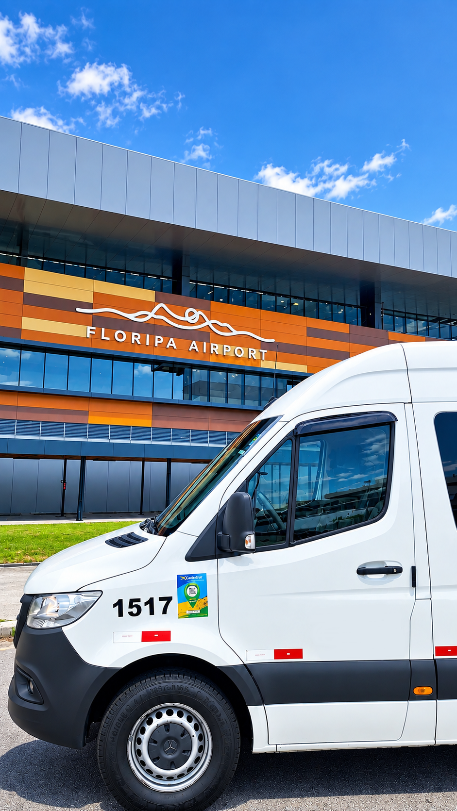 Parte frontal da van branca da Edu Tur SC diante da entrada de um terminal de passageiros.